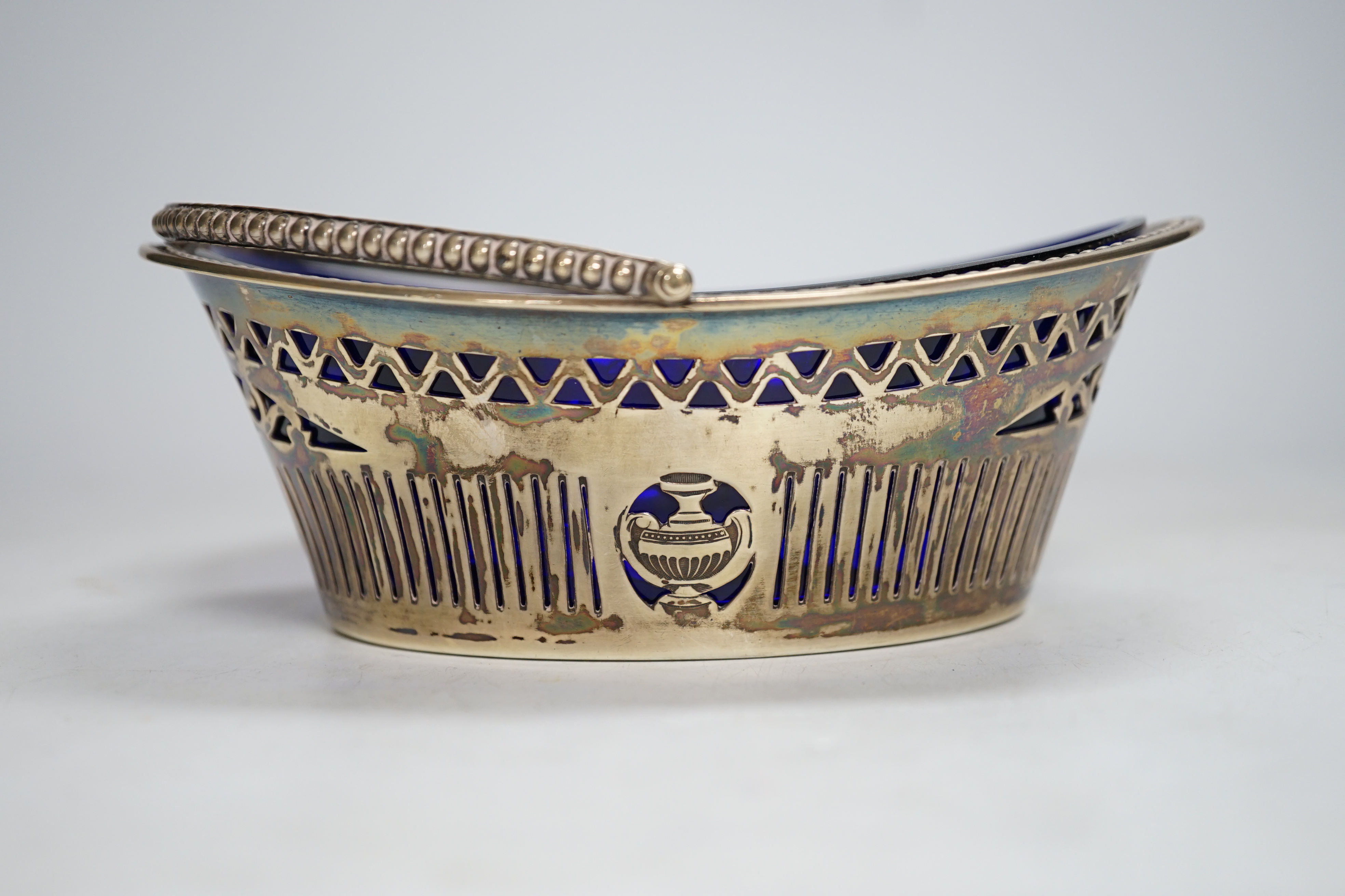A late Victorian silver oval sugar basket, J.W. Caldicott, Birmingham, 1895, with blue glass liner, length 16.3cm.